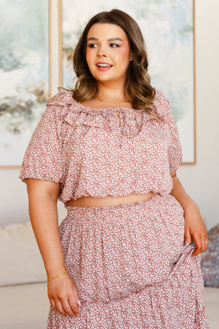 Woman wearing a pink floral dress in a room with a blurred background
