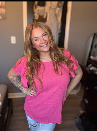 Woman wearing a pink shirt in a room with furniture and decor.
