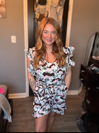 Woman wearing a patterned dress standing in a room with a baby stroller and changing table.