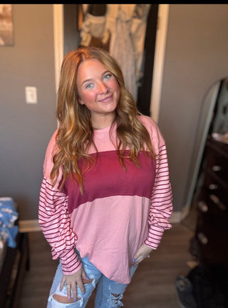 Woman wearing a pink and striped long-sleeve top in an indoor setting